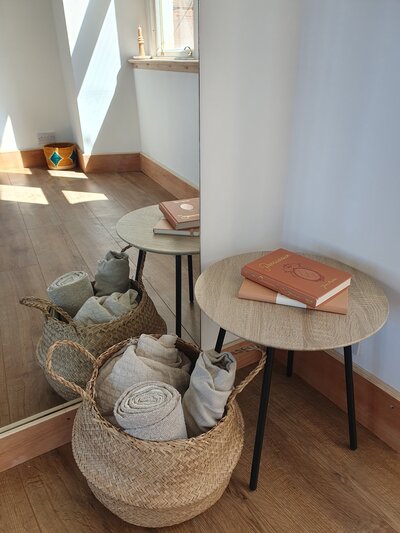Studio decorative items including a basket with blankets and a side table with books on top.