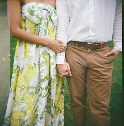 Couple holding hands and smiling in golden light, photographed on film with a soft documentary style