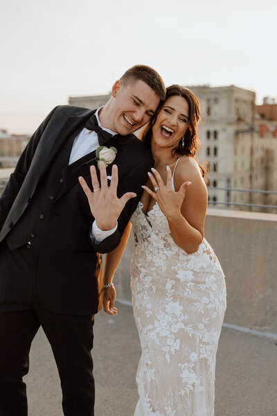 bride and groom smiling and showing off rings