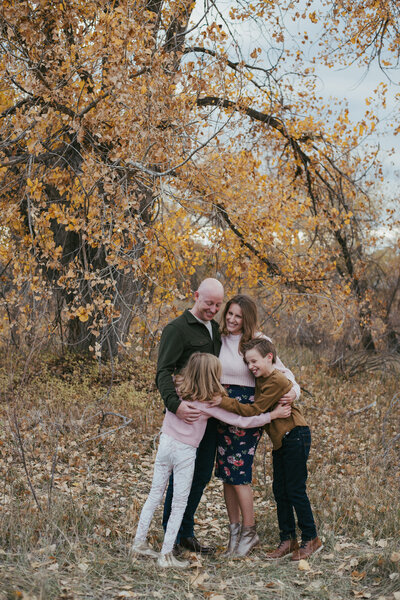 Family hugging and laughing in fall leaves