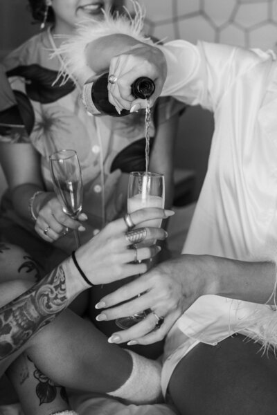 a black and white photo of a woman pouring champagne into a glass.