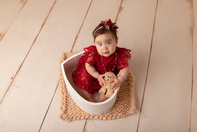 blue eyed baby in red dress sitting in a heart by milestone photographer new philadelphia