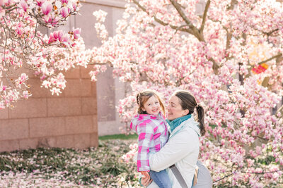 Erin Thompson holding her daughter in front of the magnolia trees