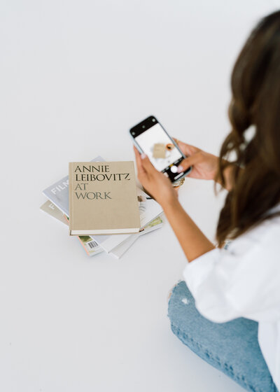 Woman taking picture of books with iphone