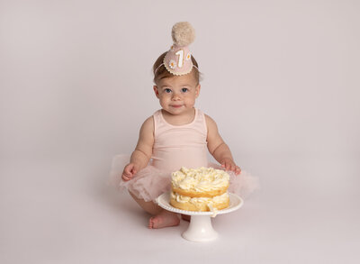 girl with a hat and cake celebrating her first birthday