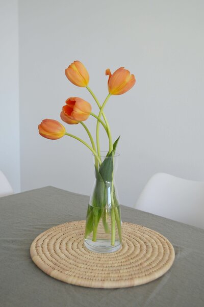 orange tulips minimalist in clear vase sitting on table