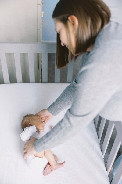 mom reaching into crib for baby