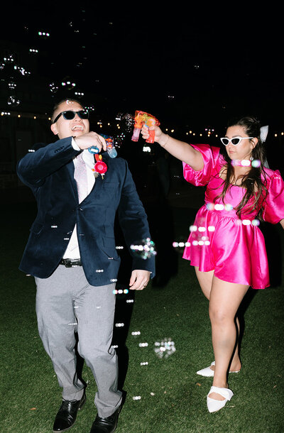 A couple holding bubble guns and pointing them at each other