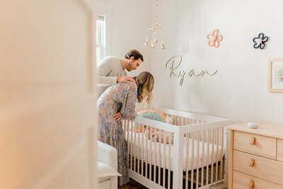 Mom and dad lean over sleeping baby's crib
