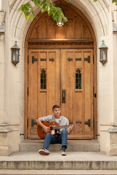 Guy Senior photos wtih his guitar framed by a downtown ornate door.