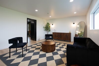 Interior of the August House venue in Dickinson, North Dakota, showing a spacious white-walled wedding reception hall with high ceilings, large windows, minimalist decor, and modern chandelier lighting.
