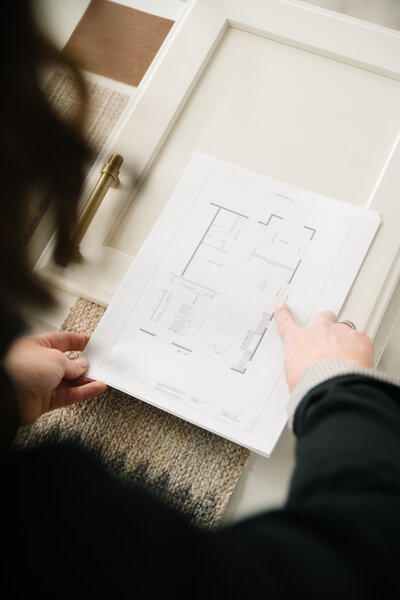 A woman points to a room shown on a floor plan