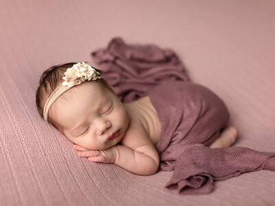 newborn baby swaddled in beige wrap for studio portraits
