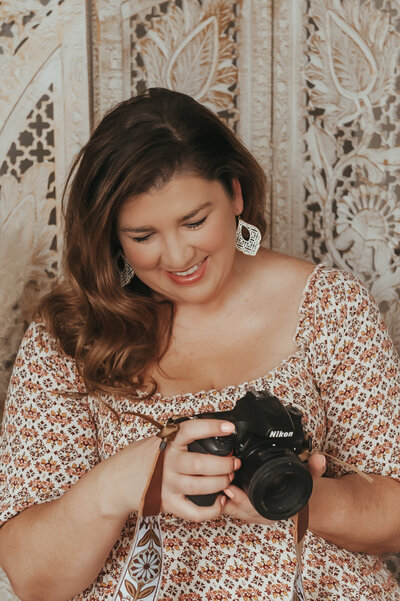 Photographer Hope Louise looking at her camera.