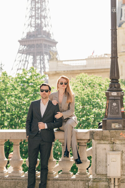 man and woman sitting on stone wall with Eiffel tower in the background