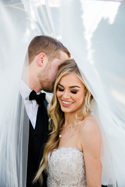 bride and groom posing under a veil at styled shoot in Knoxville