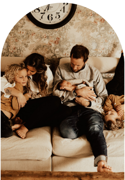 Familj sitter tillsammans i soffa med nyfödd bebis under lifestylefotografering i Halmstad