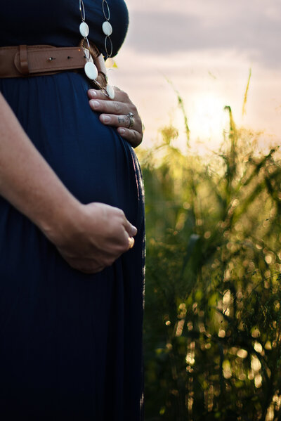 mother holding maternity belly in navy dress