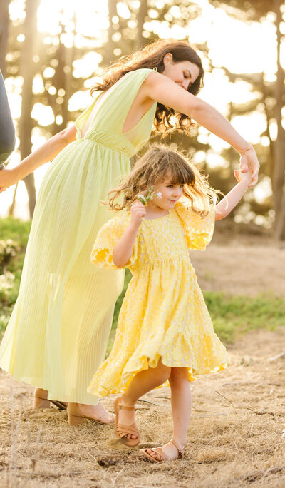 Mother twirls daughter, both wearing yellow, captured by Tevi Hardy, Bay Area