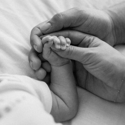 Parents handing hands with newborn
