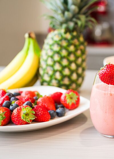 A fruit smoothie with strawberries, blueberries, a pineapple, and bananas.