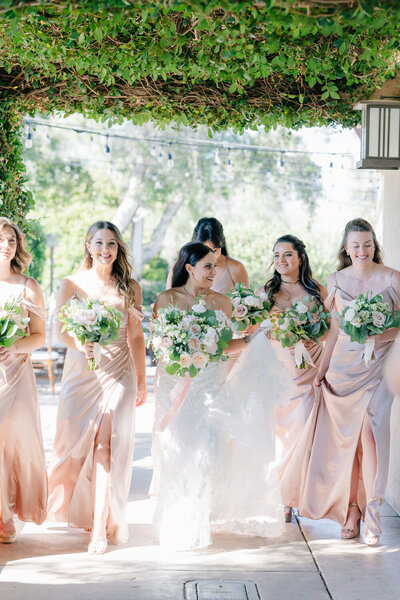 bride smiling while walking with her bridesmaids