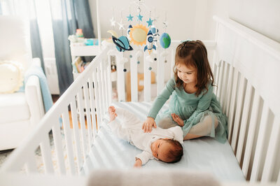 Boy putting newborn baby in a crib in nursery in Washington DC