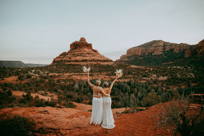 couple looking out at the red rocks both wearing white dresses
