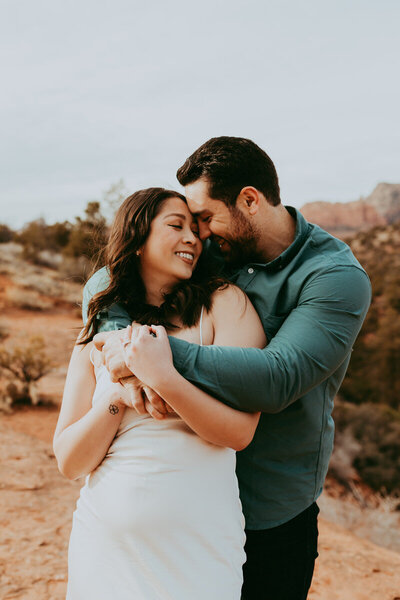 woman smiling at the camera with man hugging from behind