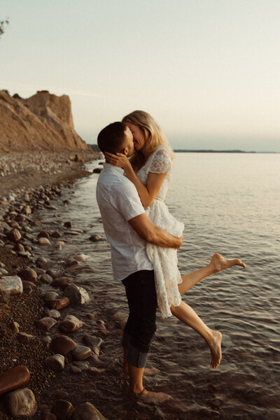 Couple kisses with the Philly waterfront and bridge behind them