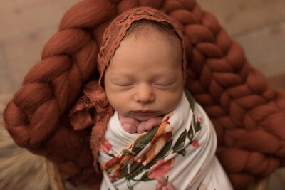 Baby girl in floral fall bonnet with burnt orange blanket
