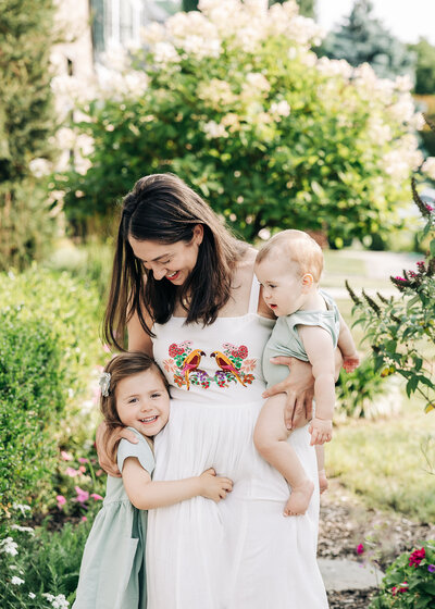 Lifestyle photo of kids hugging mom in a backyard.