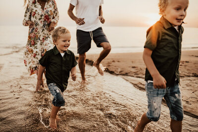 familj springer i vattenbrynet på stranden i haverdal i halmstad
