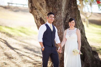 Bride and Groom hold hands as they pose for after ceremony photos under a tree at Hillcrest Park in Fullerton