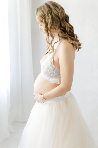 Graceful Tampa maternity portrait of mom-to-be in cream tule skirt with gentle natural light in luxury studio