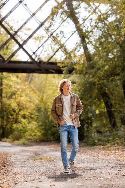 Senior guy walking through a rustic path during his Senior portrait session in Minnesota.