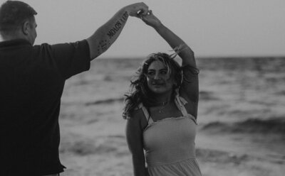 In-home gothic couples photo in Pittsburgh — black and white cinematic portrait of couple laughing while laying on ground