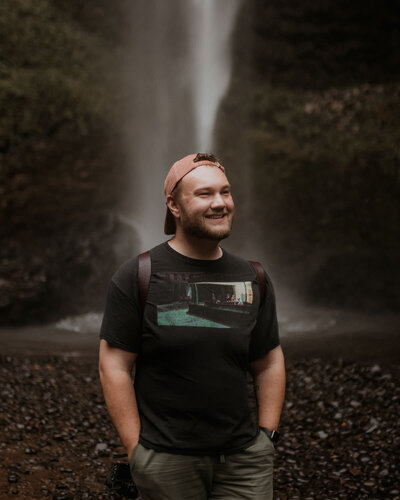 Elopement photographer Luke Payne smiling at Latourell Falls in Oregon.