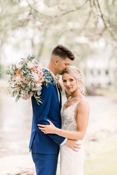 Bride and Groom in Madison Wisconsin . Bride looking at the camera holding her bouquet  designed by Reflections of You Floral by milwaukee wedding planner.