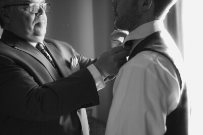 Black & White shot of groom and his father getting ready together dad tying the grooms tie