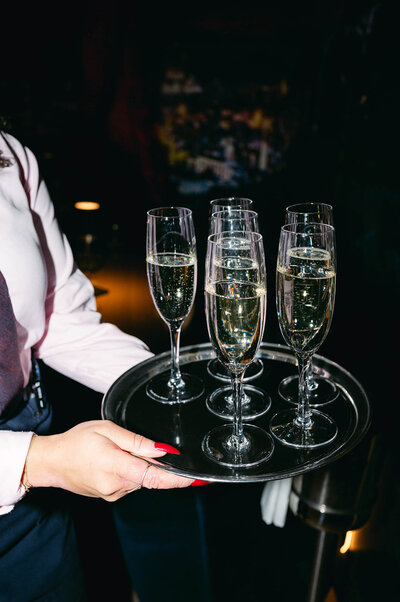 Server carrying champagne glasses during wedding