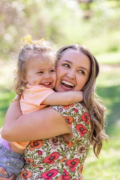 Outdoor portrait of a white woman laughing and hugging her daughter