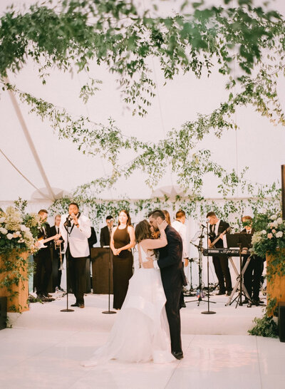 Bride and groom sharing their first dance in an event tent with garlands at a custom wedding in California