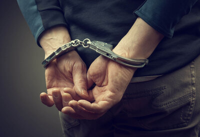 hands behind back with handcuffs to represent criminal defense