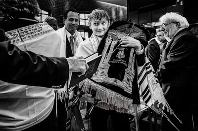 Black and white image of a boy celebrating his bar mitzvah surrounded by other people