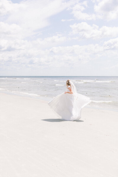 bridal portrait of bride dancing in her wedding dress on the beach
