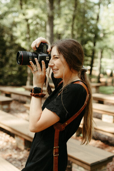 Wedding photographer holding camera and taking picture at ceremony site of a summer wedding