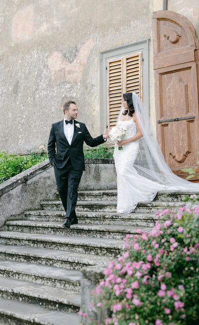 a groom helping his bride down the steps