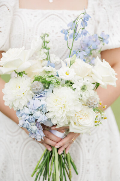 A bridal bouquet detail shot, consisting of blue, white and cream flowers.