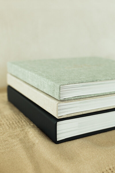3 photo albums in green, white, and navy linen stacked on each other